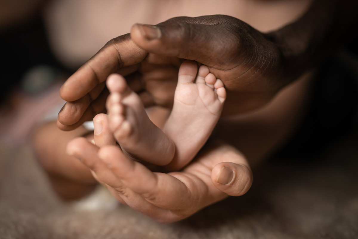 two parents' hands holding their baby's feet